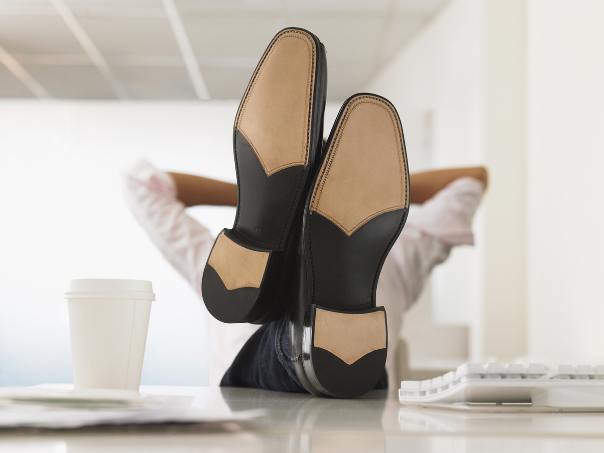Businessman Reclining With His Feet Up On Desk Executive finding work-life balance through productivity strategies